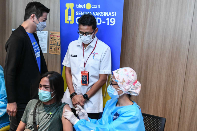 Menparekraf Sandiaga Uno (kedua kanan) didampingi Co-Founder & CMO tiket.com, Gaery Undarsa (kiri) menyaksikan vaksinasi pada warga saat peresmian Sentra Vaksinasi COVID-19 tiket.com di Jakarta (14/6). Foto: M RISYAL HIDAYAT/ANTARA FOTO
