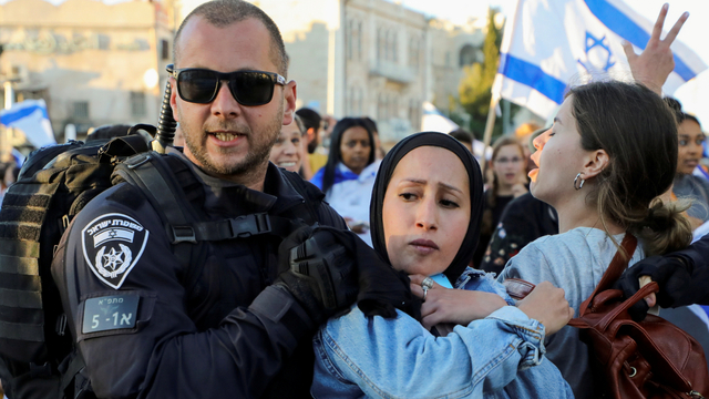 Seorang polisi Israel menggiring seorang wanita Palestina, di tengah prosesi pengibaran bendera di Gerbang Damaskus, tepat di luar Kota Tua Yerusalem, Selasa (15/6). Foto: Ammar Awad/REUTERS