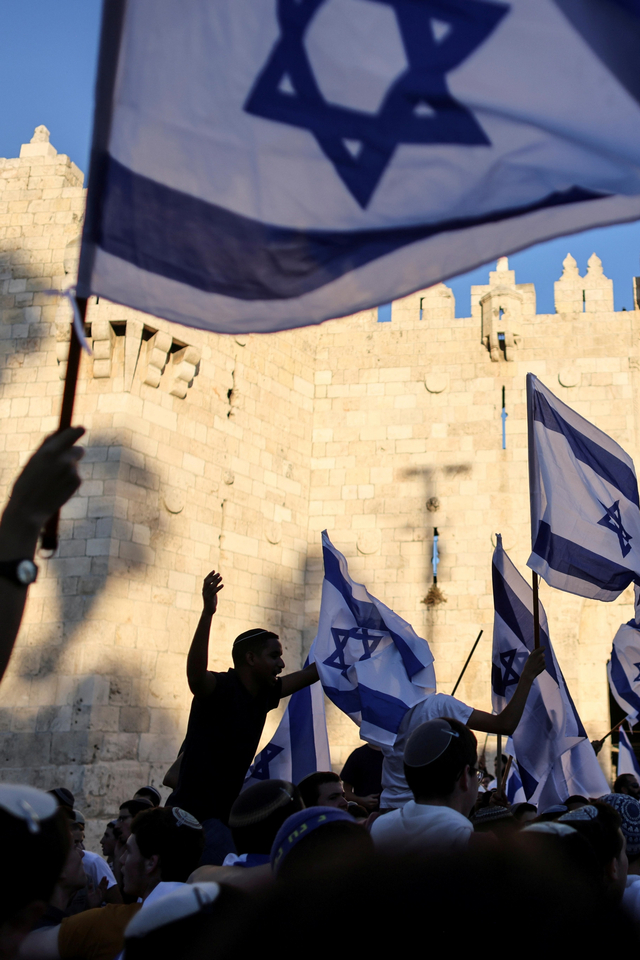 Warga Israel mengibarkan bendera di gerbang Damaskus di luar Kota Tua Yerusalem, di Yerusalem, Selasa (15/6). Foto: Ronen Zvulun/REUTERS