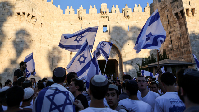 Warga Israel mengibarkan bendera di gerbang Damaskus di luar Kota Tua Yerusalem, di Yerusalem, Selasa (15/6). Foto: Ronen Zvulun/REUTERS