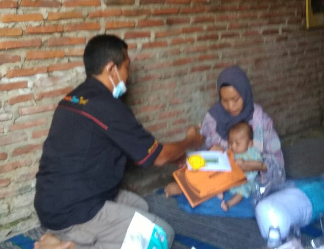 Mardiyani yang memangku anaknya menerima bantuan yang diserahkan KWT. (bentar/panturpost.com)
