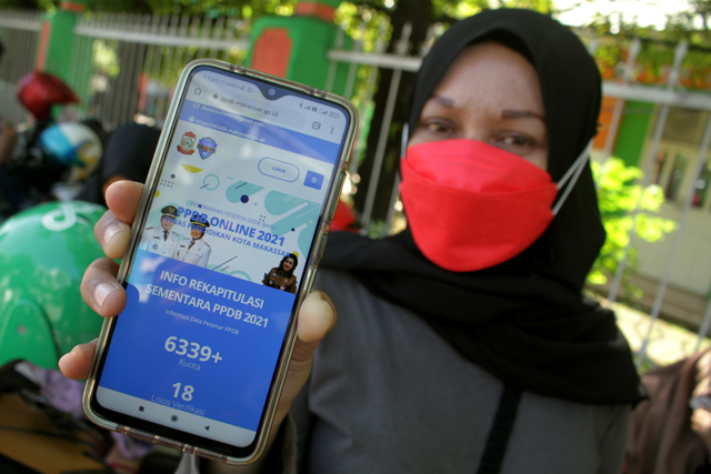 Orang tua calon siswa menunjukkan situs web pendaftaran Penerimaan Peserta Didik Baru (PPDB) 2021. Foto: ANTARA FOTO/Arnas Padda