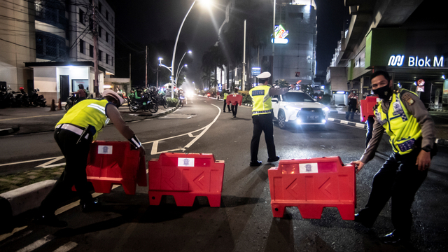 Petugas kepolisian menyusun pembatas jalan saat akan melakukan penutupan jalan di kawasan Bulungan, Jakarta, Senin (21/6/2021). Foto: Muhammad Adimaja/ANTARA FOTO