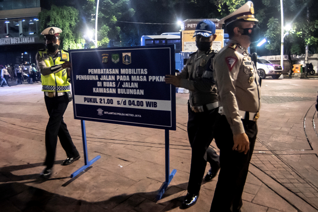 Petugas kepolisian meletakkan papan informasi saat melakukan penutupan jalan di kawasan Bulungan, Jakarta, Senin (21/6/2021). Foto: Muhammad Adimaja/ANTARA FOTO