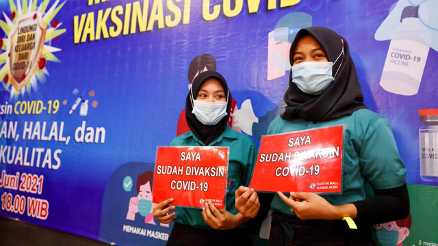 Pekerja di mall menunjukkan poster telah divaksin. Foto: Suparta/acehkini