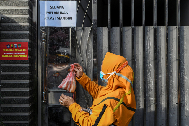 Anggota satuan tugas penanganan COVID-19 menggantungkan makanan di pagar rumah warga yang menjalani isolasi mandiri di kawasan Warakas. Foto: M Risyal Hidayat/Antara Foto