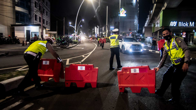 Petugas kepolisian menyusun pembatas jalan saat akan melakukan penutupan jalan dalam rangka pembatasan mobilitas warga guna menekan penyebaran COVID-19 di kawasan Bulungan, Jakarta, Senin (21/6/2021). Foto: Muhammad Adimaja/ANTARA FOTO