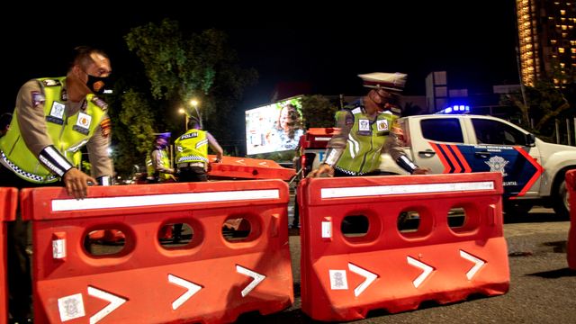 Petugas kepolisian menyusun pembatas saat akan menutup jalan di Jalan POM IX, Palembang, Sumatera Selatan, Rabu (23/6/2021). Foto: Nova Wahyudi/ANTARA FOTO