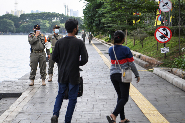 Petugas Satpol PP meminta warga meninggalkan kawasan Danau Sunter Timur yang tengah ditutup sementara di Jakarta, Kamis (24/6/2021). Foto: Hafidz Mubarak A/Antara Foto