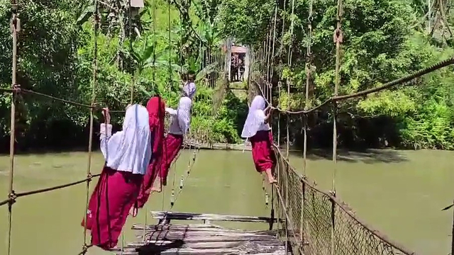 Pelajar SD menyeberangi jembatan gantung rusak di Desa Pamoseang, Mamasa, Sulawesi Barat, dengan cara bergelantungan. Foto: Dok. Istimewa