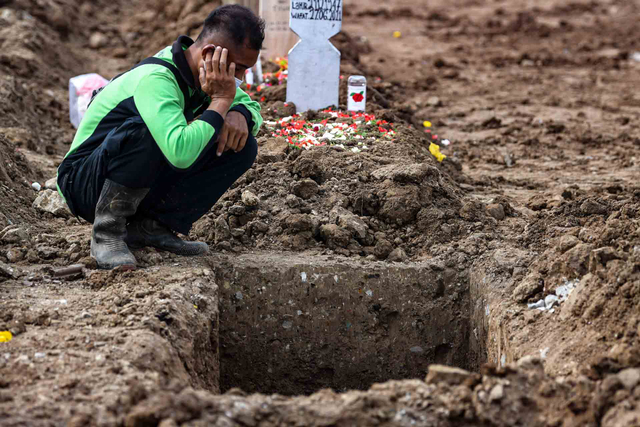 Petugas mengumandangkan adzan saat pemakaman jenazah dengan protokol COVID-19 di TPU Rorotan, Cilincing, Jakarta Utara, Senin (28/6/2021). Foto: M Risyal Hidayat/ANTARA FOTO