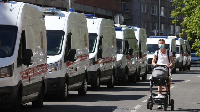 Seorang wanita berjalan melewati ambulans yang diparkir di luar Rumah Sakit di Saint Petersburg, Rusia (17/6). Foto: Alexander Demianchuk/TASS via Reuters