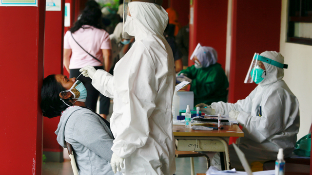 Seorang petugas kesehatan mengambil sampel swab dari seorang wanita di sebuah sekolah di Jakarta, Jumat (2/7). Foto: Ajeng Dinar Ulfiana/REUTERS