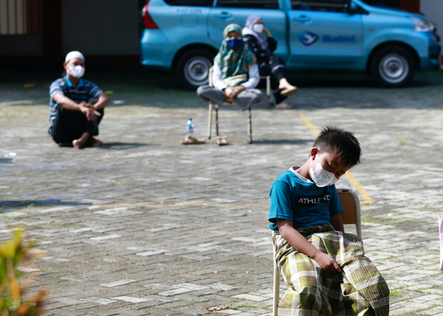 Seorang anak laki-laki tertidur saat menunggu untuk tes swab antigen di sebuah sekolah di Jakarta, Jumat (2/7). Foto: Ajeng Dinar Ulfiana/REUTERS