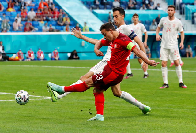 Pemain Swiss Xherdan Shaqiri berebut bola dengan pemain Spanyol Sergio Busquets pada perempat final Euro 2020 di Stadion Saint Petersburg, Rusia. Foto: Maxim Shemetov/Reuters