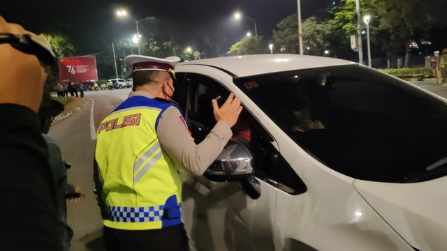 Petugas memeriksa keperluan dan tujuan dari pengendara di Kawasan Bundaran Senayan, Jakarta, Sabtu (3/7/2021) dini hari. Foto: Ricky Prayoga/Antara