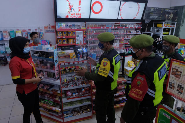 Petugas Linmas Desa Sumerta Kelod menegur karyawan toko modern yang beraktivitas hingga larut saat PPKM darurat di Denpasar, Bali, Jumat (2/7/2021). Foto: Nyoman Hendra Wibowo/Antara Foto