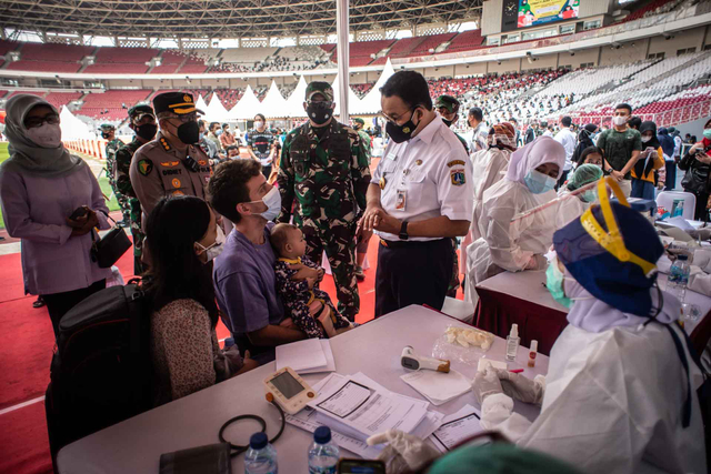 Gubernur DKI Jakarta Anies Baswedan (kanan) berbincang dengan warga calon penerima vaksin COVID-19 saat meninjau vaksinasi COVID-19 massal di Stadion Utama Gelora Bung Karno, Senayan, Jakarta, Sabtu (3/7/2021). Foto: Aprillio Akbar/ANTARA FOTO