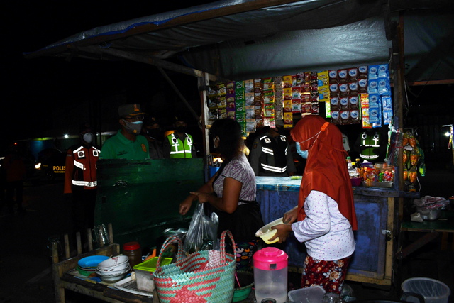 Petugas gabungan menegur pedagang kaki lima yang melanggar jam operasional hingga pukul 20.00 WIB saat melakukan patroli di Kota Madiun, Jawa Timur, Sabtu (3/7/2021) malam. Foto: Siswowidodo/Antara Foto