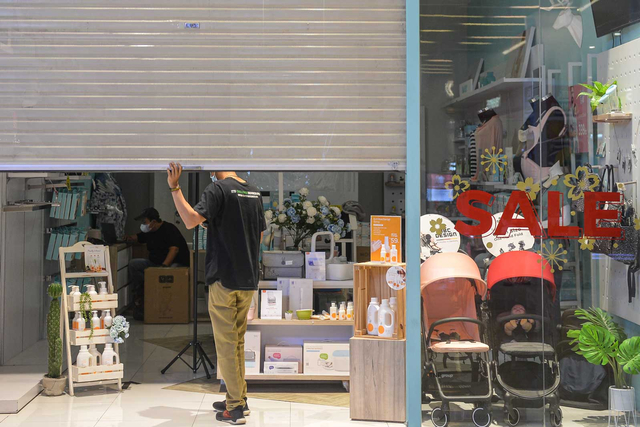 Seorang pegawai menutup tokonya saat hari ke tiga PPKM Darurat di salah satu Mal di Jakarta, Senin (5/7/2021). Foto: M RISYAL HIDAYAT/ANTARA FOTO