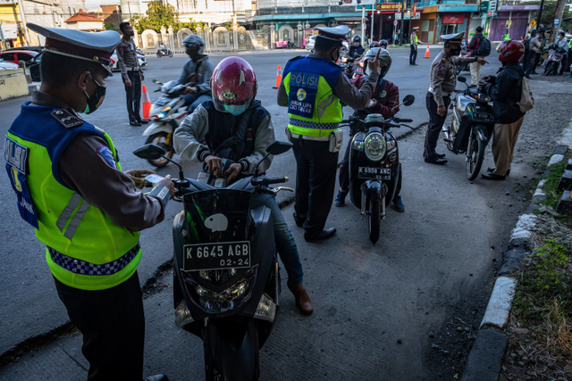Personel kepolisian Satlantas Polres Demak memeriksa kelengkapan surat melintas kota/kabupaten terhadap pengendara bernomor polisi luar kota saat operasi penyekatan PPKM Darurat di Kabupaten Demak, Jawa Tengah, Selasa (6/7).  Foto: Aji Styawan/ANTARA FOTO