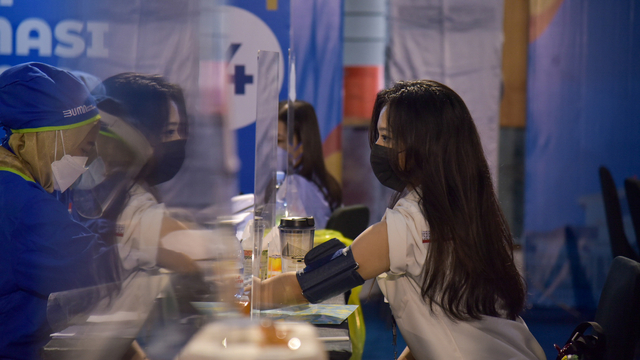 Petugas kesehatan memeriksa kesehatan warga calon penerima vaksin COVID-19 di Sentra Vaksinasi Bersama BUMN. Foto: ANTARA FOTO/Fransisco Carolio