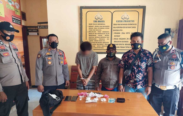 Anggota Polsek Nuhon bersama pelaku setelah diamankan di di Jalan Trans Sulawesi, Kecamatan Nuhon, Kabupaten Banggai, Sulteng, Rabu (7/7). [Foto: Istimewa]