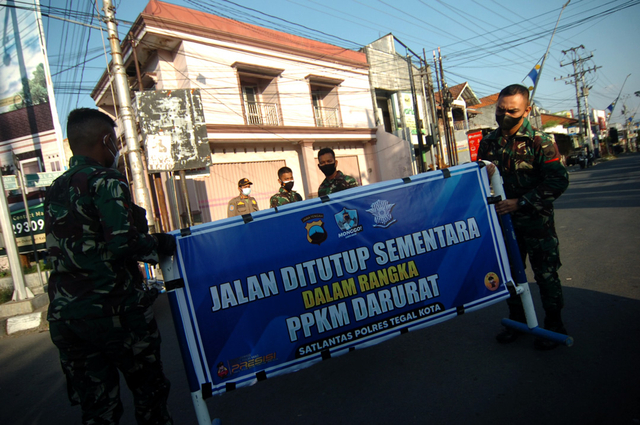 Prajurit TNI mengangkat pembatas jalan saat penutupan jalan di perbatasan Tegal-Slawi, Jawa Tengah, Rabu (7/7/2021). Foto: Oky Lukmansyah/ANTARA FOTO
