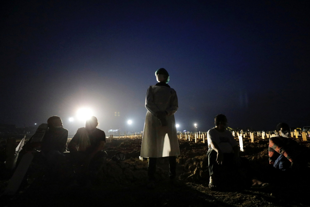 Petugas pemakaman beristirahat usai memakamkan sejumlah jenazah dengan protokol COVID-19 di TPU Rorotan, Cilincing, Jakarta, Rabu (7/7). Foto: Willy Kurniawan/REUTERS