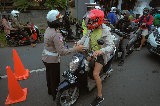 Anggota Polisi meminta Warga Negara Asing (WNA) yang tidak melengkapi persyaratan untuk putar balik saat penyekatan PPKM Darurat di Pos Teuku Umar Barat - Gunung Salak, Denpasar, Bali, Kamis (8/7/2021). Foto: Nyoman Hendra Wibowo/ANTARA FOTO