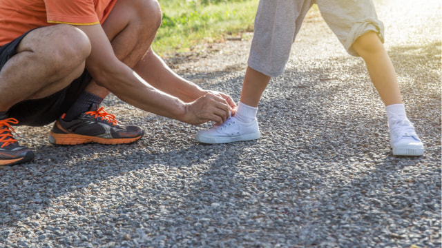 Ilustrasi orang tua membantu anak mengikat tali sepatunya. Foto: Shutterstock