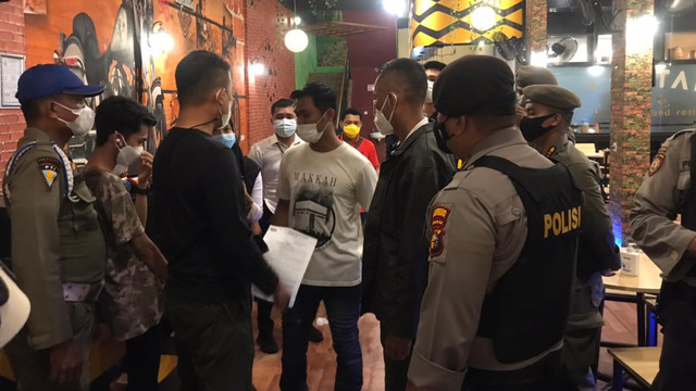 TIM Gabungan terdiri dari Satpol PP, Polisi dan TNI memberikan surat teguran ke pengelola kafe di Jalan Arifin Achmad, Pekanbaru, kedapatan melanggar aturan PPKM Skala Mikro, Kamis malam (9/7/2021).