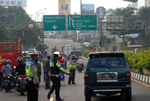 Anggota Satlantas Polres Bogor mengarahkan pengendara mobil untuk berputar arah saat penyekatan jalur Puncak di Simpang Gadog, Kabupaten Bogor, Jawa Barat, Sabtu (10/7/2021). Foto: ARIF FIRMANSYAH/ANTARA FOTO