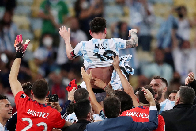 Pemain Argentina Lionel Messi dilempar ke udara oleh rekan setimnya usai menjuarai Copa America 2021 mengalahkan Brasil di Estadio Maracana, Rio de Janeiro, Brasil. Foto: Ricardo Moraes/REUTERS