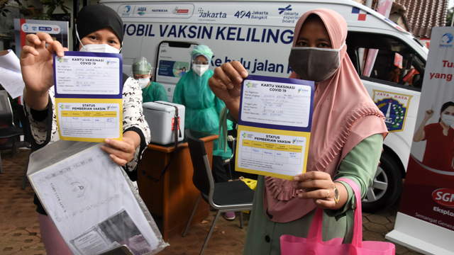 Dua warga menunjukkan kartu vaksinasi COVID-19 usai mengikuti vaksinasi dari mobil vaksin keliling yang singgah di Kantor Kelurahan Cipedak, Jakarta, Selasa (13/7/2021). Foto: Indrianto Eko Suwarso/ANTARA FOTO
