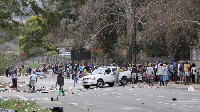 Orang-orang berdiri di pinggir jalan setelah diusir menyusul protes yang melebar menjadi penjarahan, di Durban, Afrika Selatan. Foto: Kierran Allen/via REUTERS