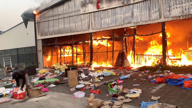 Kebakaran melanda Campsdrift Park, yang menampung Makro dan China Mall, menyusul protes yang meluas menjadi penjarahan di Pietermaritzburg, Afrika Selatan 13 Juli 2021. Foto: Sibonelo Zungu/via REUTERS