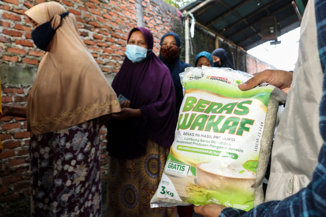 Warga mengantri pembagian Beras Wakaf dari ACT