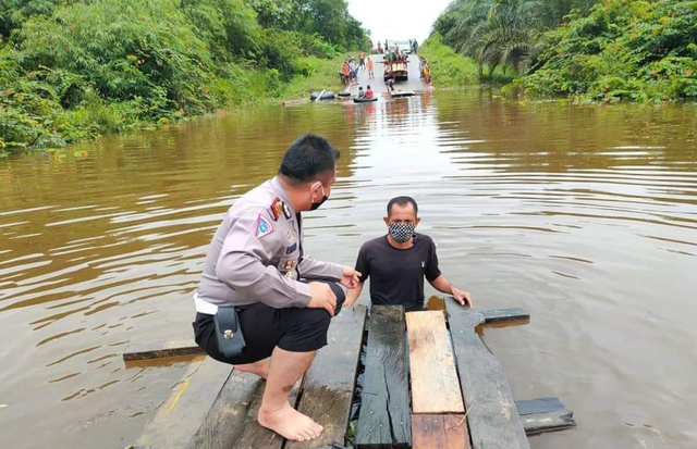 Salah satu anggota polisi bersama warga saat mengecek debit air di salah satu titik jalan yang berdampak pad kemacetan. (FOTO: Dokumen Polres Lamandau).