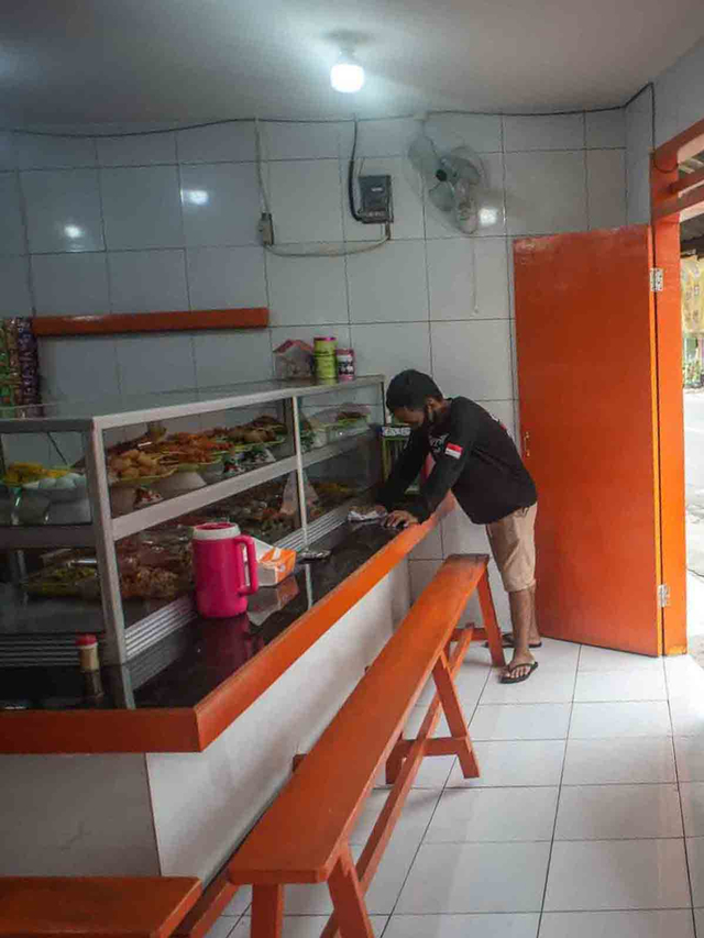 Pekerja membersihkan meja makan di Warteg Subsidi Bahari, Pejaten, Jakarta, Kamis (22/7/2021). Foto: Aprillio Akbar/ANTARA FOTO