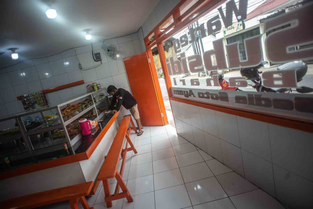 Pekerja membersihkan meja makan di warteg. Foto: Aprillio Akbar/ANTARA FOTO