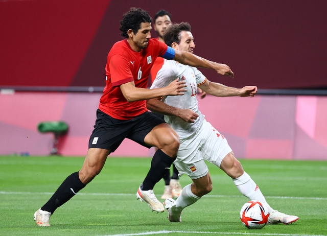 Pemain Mesir Ahmed Hegazy duel dengan pemain Spanyol Mikel Oyarzabal saat pertandingan Olimpiade Tokyo 2020 di Sapporo Dome, Jepang. Foto: Kim Hong-Ji/Reuters