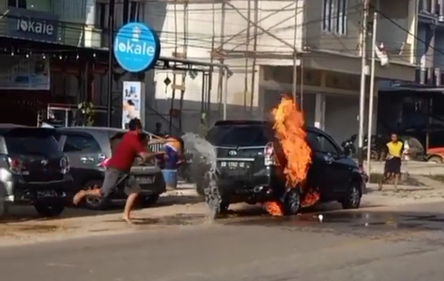 Warga berusaha memadamkan api yang keluar dari Toyota Avanza hitam yang parkir di depan Lokale Sekadau. Foto: Dok Hi!Pontianak