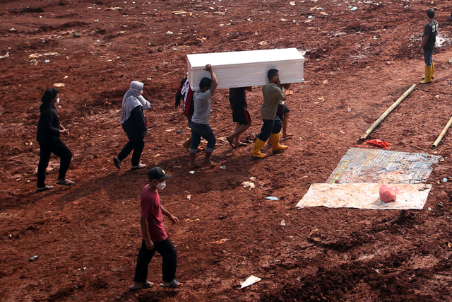 Petugas mengusung peti jenazah untuk dimakamkan di lahan baru tempat pemakaman umum (TPU) khusus COVID-19, Jombang, Tangerang Selatan, Banten, Jumat (23/7/2021). Foto: Muhammad Iqbal/Antara Foto