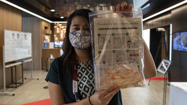 Seorang jurnalis peliput Olimpade Tokyo menunjukkan alat tes PCR COVID-19 dengan metode saliva di Shinjuku, Tokyo, Jepang, Senin (19/7/2021). Foto: Sigid Kurniawan/Antara Foto