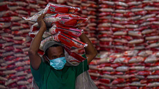 Pekerja yang mengenakan masker memanggul beras bantuan PPKM saat proses penyaluran di Gudang Perum Bulog Kantor Wilayah Sumatera Utara, Senin (26/7/2021). Foto: Fransisco Carolio/ANTARA FOTO