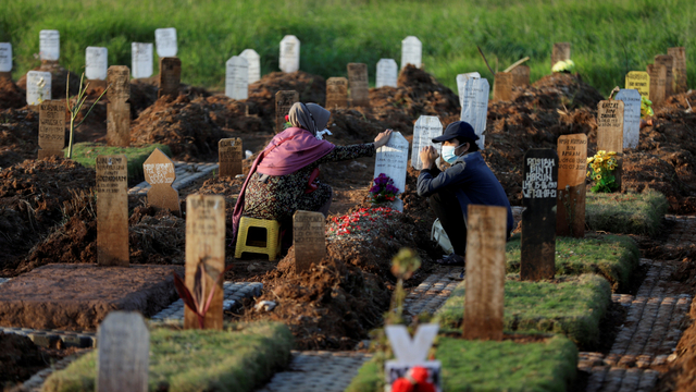 Warga berziarah di dekat pusara keluarganya di area pemakaman khusus COVID-19 di Bekasi, Jawa Barat, Selasa (27/7). Foto: Willy Kurniawan/REUTERS