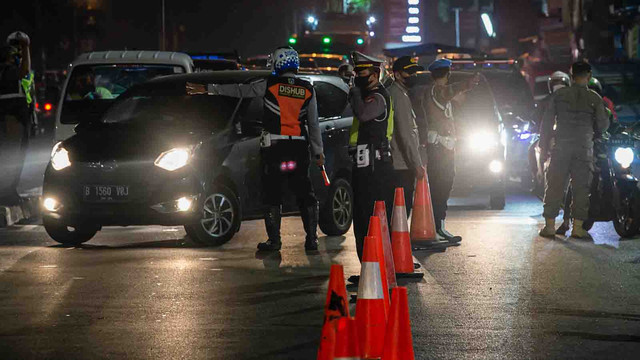 Petugas gabungan mengarahkan mobil untuk memutar balik saat pelaksanaan Pemberlakuan Pembatasan Kegiatan Masyarakat (PPKM) Darurat di Jalan Raya Bogor, Jakarta. Foto: M RISYAL HIDAYAT/ANTARA FOTO