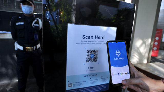Pengunjung memindai QR Code dengan aplikasi PeduliLindungi saat mengunjungi mal. Foto: Fikri Yusuf/ANTARA FOTO