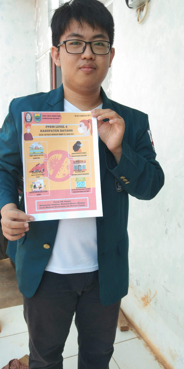 Gambar 1: Archie Tobias Kiatanto, Mahasiswa UNDIP memegang poster himbauan PPKM Level 4 (Sumber: Dokumentasi Pribadi)